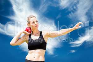 Composite image of front view of sportswoman practising shot put