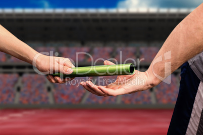 Composite image of man passing the baton to partner on track