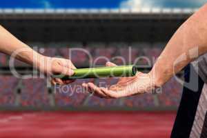 Composite image of man passing the baton to partner on track