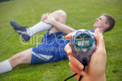 Composite image of a hand holding a timer against football playe