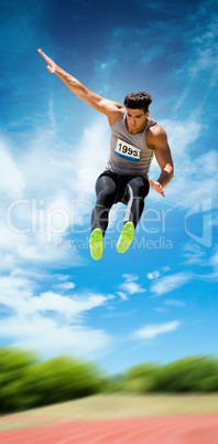 Sportsman jumping against athletics field
