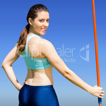 Composite image of rear view of sporty woman holding a javelin