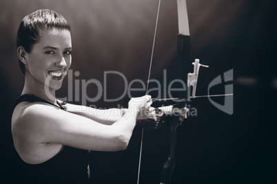 Composite image of portrait of sportswoman is smiling and practising archery