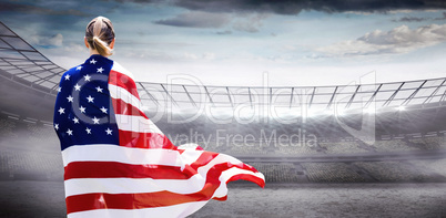 Composite image of rear view of sporty woman holding an american Composite image of rear view of sporty woman holding an american