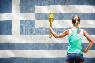 Composite image of rear view of sporty woman holding olympic tor