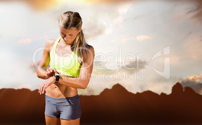 Composite image of sporty woman looking her watch