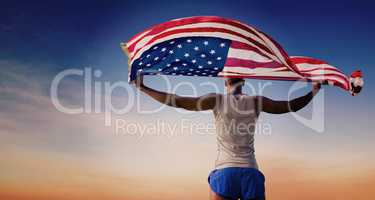 Composite image of rear view of sportsman holding american flag