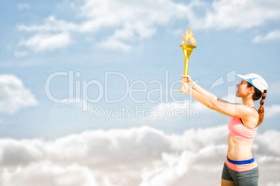 Composite image of sporty woman holding olympic torch