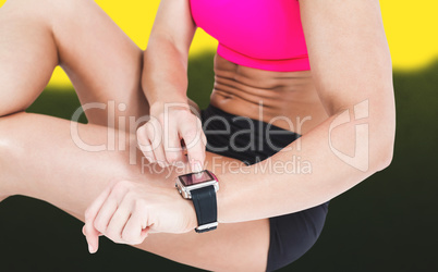Composite image of female athlete sitting and using her smart wa