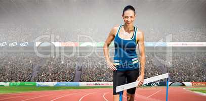 Composite image of portrait of sportswoman posing next to hurdle