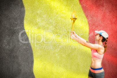 Composite image of sporty woman holding olympic torch