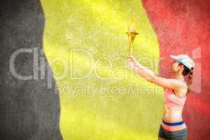Composite image of sporty woman holding olympic torch