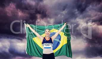 Composite image of athlete posing with brazilian flag after vict