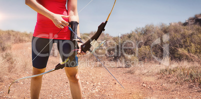 Composite image of focus on sportswoman holding an arch