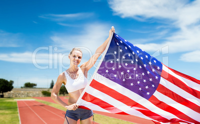 Composite image of happy sportswoman holding an american flag