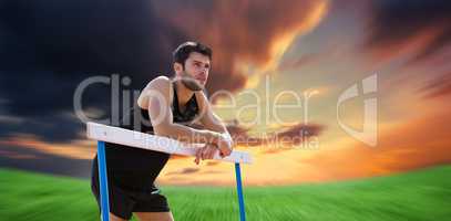 Composite image of athletic man pressed on a hurdle posing