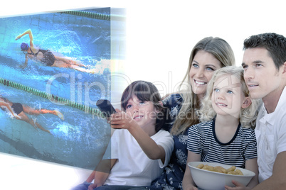 Composite image of smiling family watching a film at television