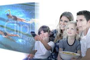 Composite image of smiling family watching a film at television