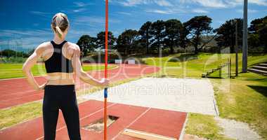 Composite image of rear view of sportswoman is posing with a javelin
