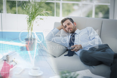 Composite image of businessman is watching sport on television
