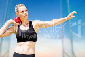 Composite image of front view of sportswoman practising shot put