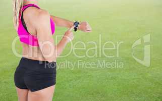 Composite image of female athlete using her smart watch