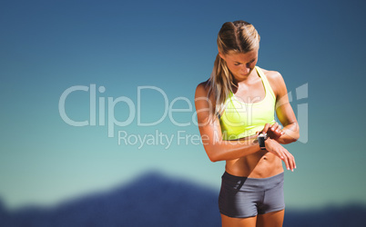 Composite image of sporty woman looking her watch