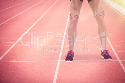 Composite image of tired athlete standing with hand on knee