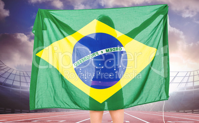 Composite image of athlete posing with brazilian flag after vict