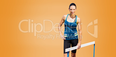Portrait of sportswoman posing next to hurdle