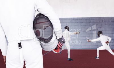 Composite image of rear view of swordsman holding fencing mask a