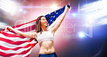 Happy sportswoman posing with an american flag  against composit