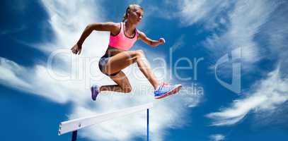 Composite image of sporty woman jumping a hurdle