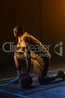 Portrait of basketball player with a knee on the floor and a han