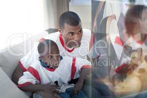 Composite image of father and son are watching sport on televisi