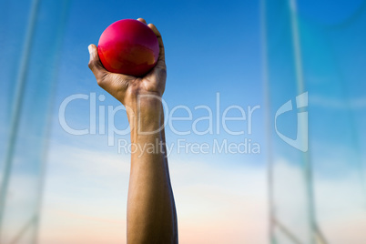 Composite image of hand holding a red ball