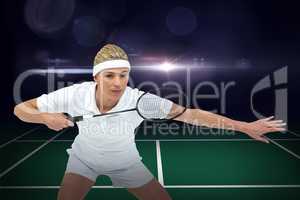 Composite image of female athlete holding a badminton racket rea