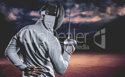 Composite image of man wearing fencing suit practicing with swor