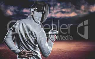 Composite image of man wearing fencing suit practicing with swor