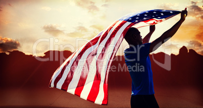 Composite image of rear view of sportsman raising an american fl