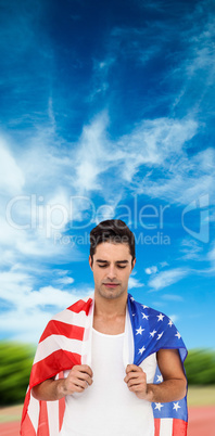 Athlete with american flag wrapped around his body against athle