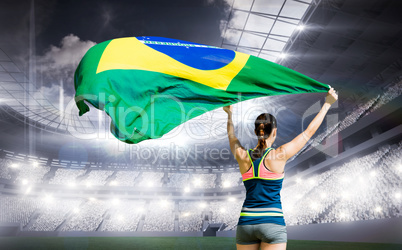 Composite image of rear view of sportswoman raising a brazilian