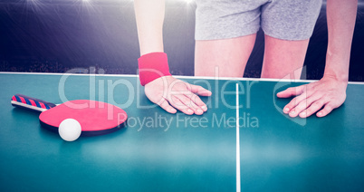 Composite image of female athlete leaning on ping pong table