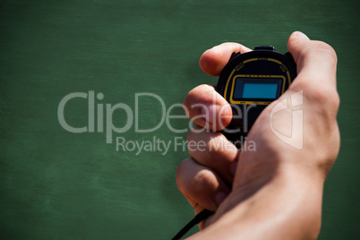 Close up of hand holding a chronometer against green chalkboard