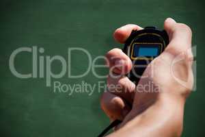 Close up of hand holding a chronometer against green chalkboard