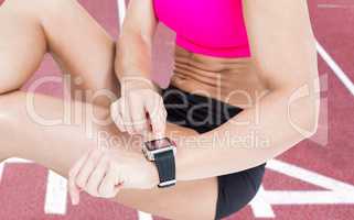 Composite image of female athlete sitting and using her smart wa