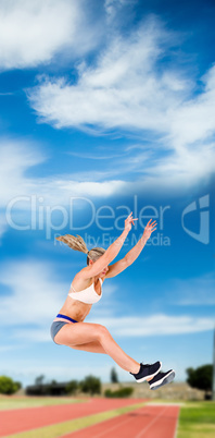 Female athlete jumping against athletics field