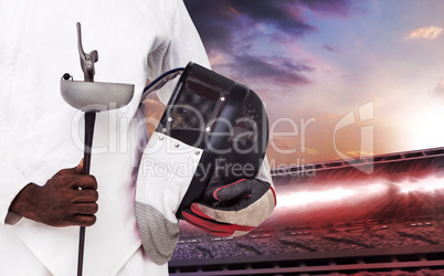 Composite image of mid-section of man standing with fencing mask