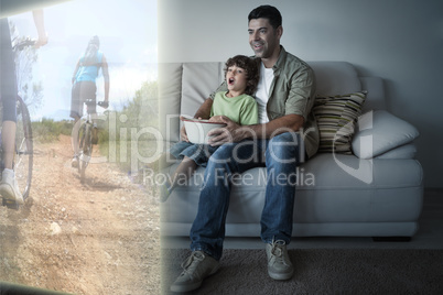 Composite image of father and son are watching biking on televis