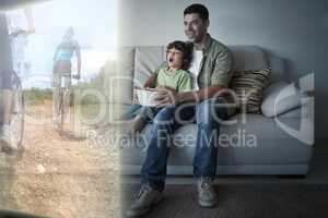 Composite image of father and son are watching biking on televis